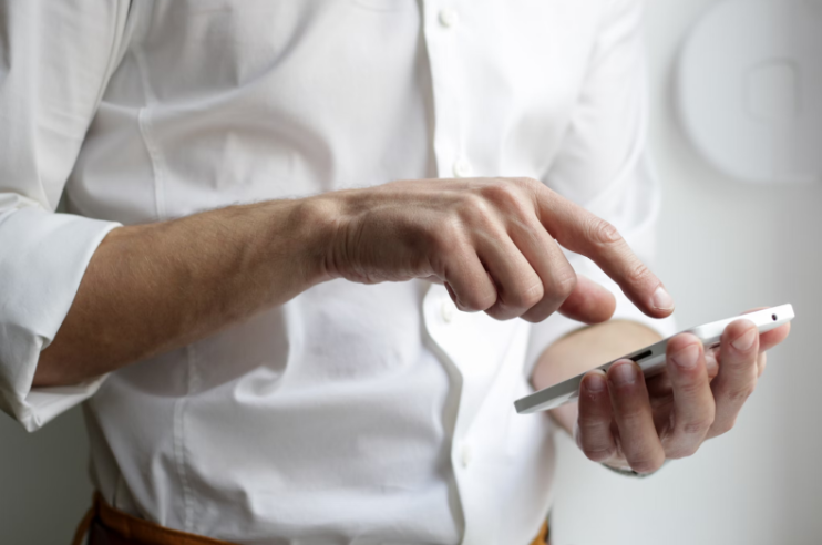 Ein Mann in einer weißen Shorts mit einem Smartphone